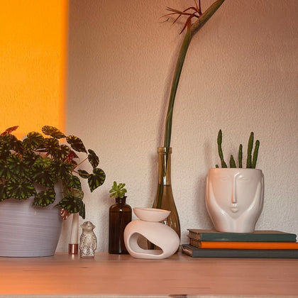 Handcrafted ceramic wax burner styled on a wooden shelf with plants, books, and warm lighting for a cozy and elegant home ambiance.